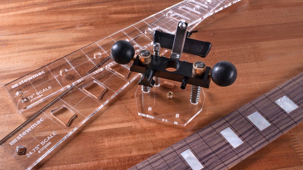 Guitar fingerboard with block inlays next to tools and templates to rout for inlays.